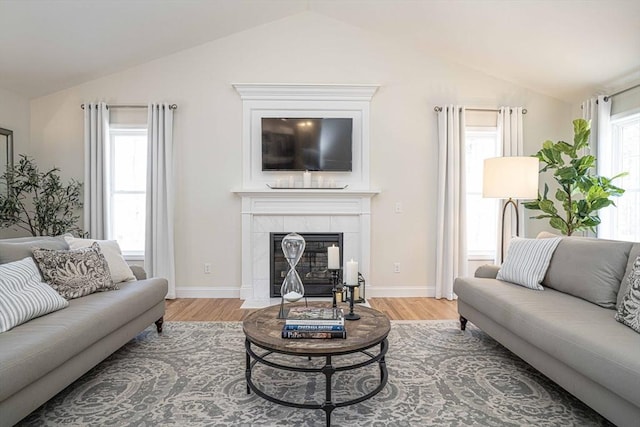 living room featuring hardwood / wood-style flooring, a tiled fireplace, and a healthy amount of sunlight