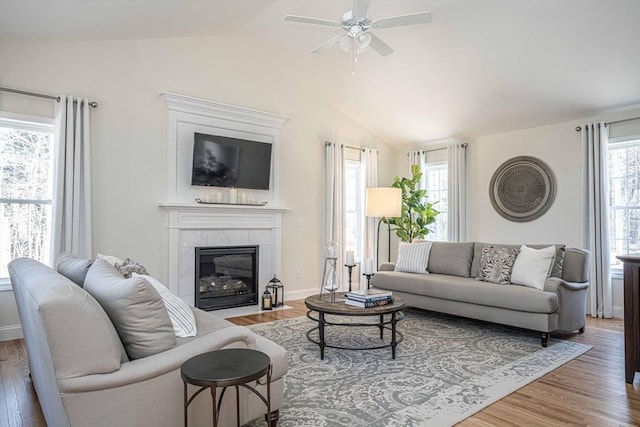 living room with ceiling fan, lofted ceiling, a fireplace, and hardwood / wood-style floors