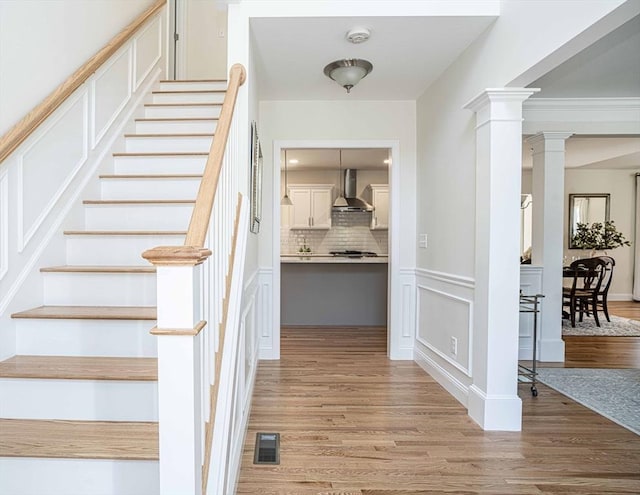 stairs with decorative columns and hardwood / wood-style floors