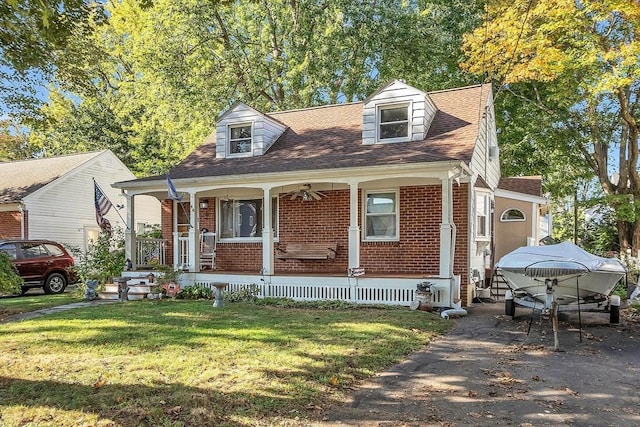 cape cod home with a front yard, covered porch, brick siding, and a shingled roof