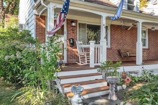 view of exterior entry featuring a porch, brick siding, and a shingled roof