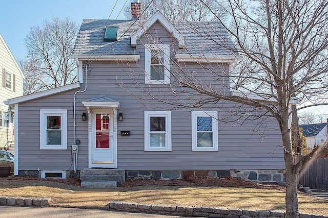 view of front of home featuring a front lawn, roof with shingles, a chimney, and entry steps