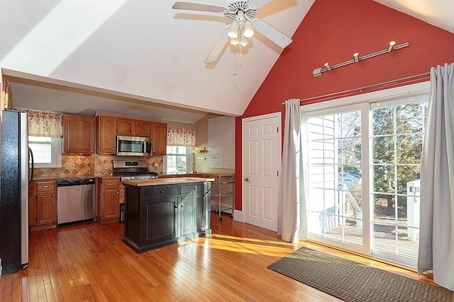 kitchen featuring a center island, stainless steel appliances, light wood-style floors, and tasteful backsplash