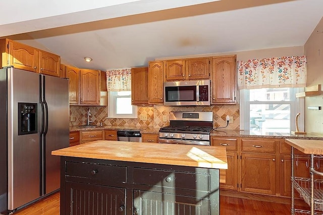 kitchen featuring a sink, decorative backsplash, wooden counters, and appliances with stainless steel finishes