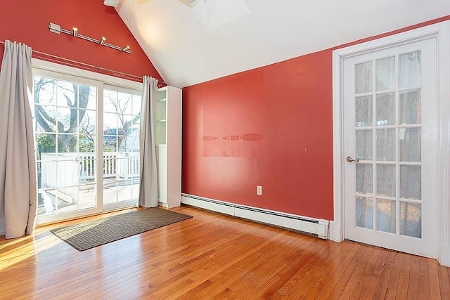 spare room featuring baseboard heating, hardwood / wood-style flooring, and vaulted ceiling