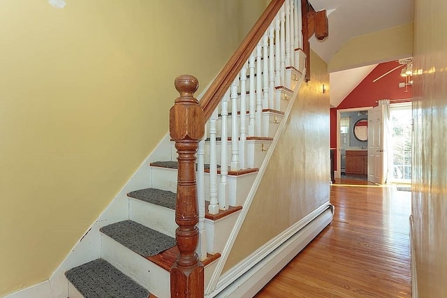 stairs with wood finished floors and a baseboard radiator