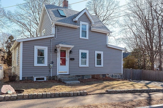 view of front of home featuring entry steps, fence, roof with shingles, and a chimney