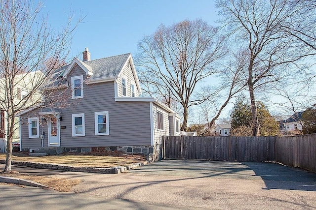 view of front of house with a gate, a shingled roof, a chimney, and fence