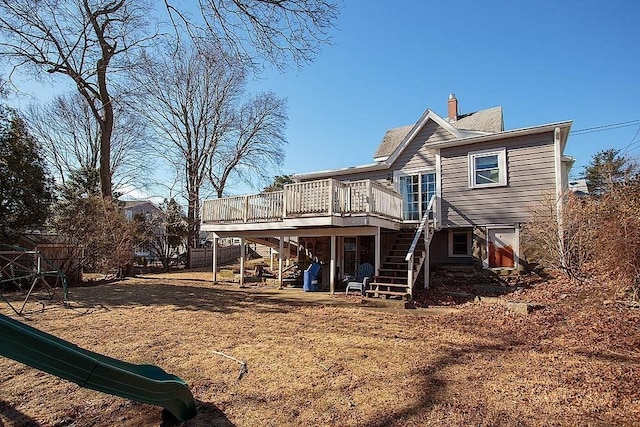 rear view of house with a deck, stairway, fence, and a chimney