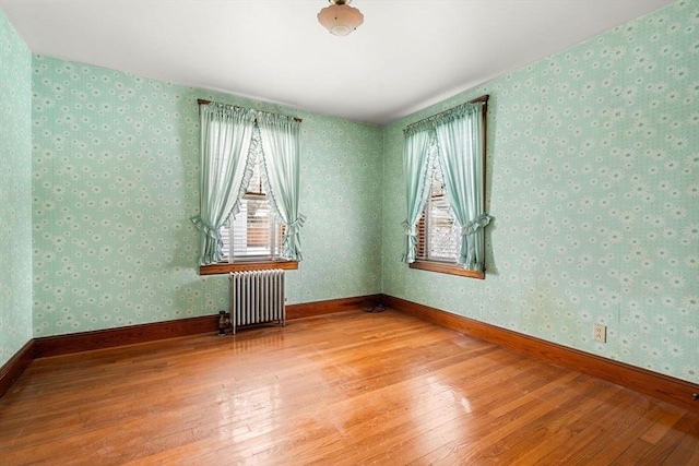 unfurnished room featuring hardwood / wood-style floors and radiator heating unit