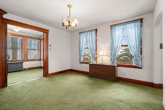 carpeted spare room featuring a notable chandelier and radiator