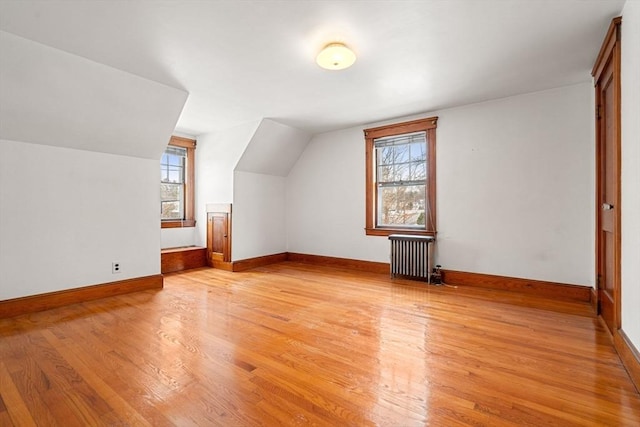 additional living space featuring lofted ceiling, radiator heating unit, and light hardwood / wood-style floors