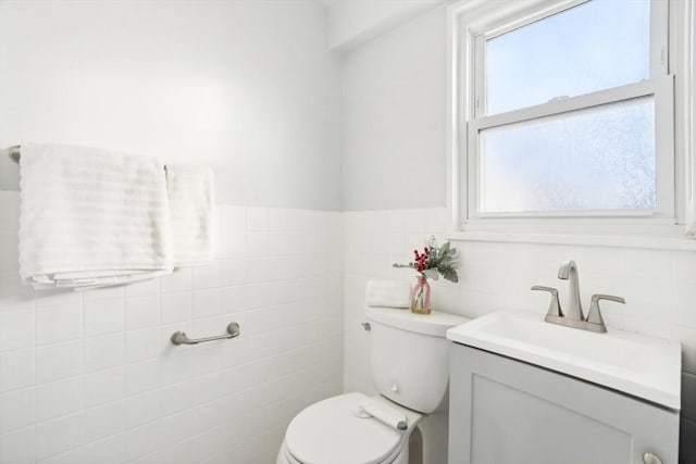 bathroom featuring vanity, toilet, and tile walls