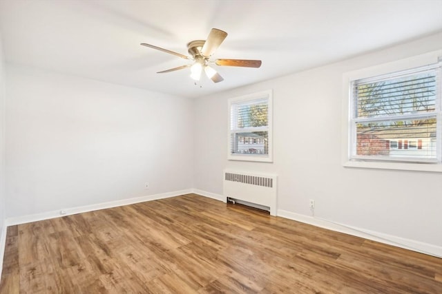 empty room featuring hardwood / wood-style flooring, ceiling fan, and radiator