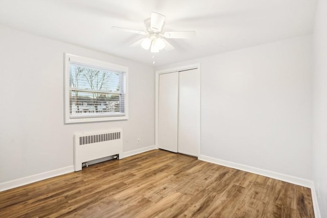 spare room featuring hardwood / wood-style floors, ceiling fan, and radiator