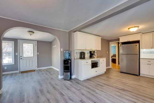 kitchen with built in microwave, white cabinetry, stainless steel fridge, and light wood-type flooring