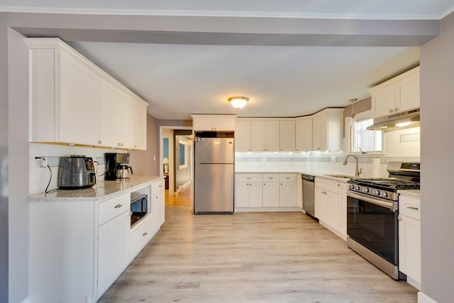 kitchen with sink, appliances with stainless steel finishes, pendant lighting, light hardwood / wood-style floors, and white cabinets