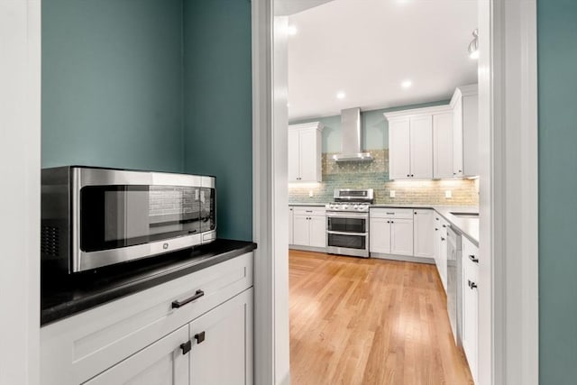 132 Sewall St Unit C, Brookline, MA 02446 - kitchen featuring wall chimney exhaust hood, stainless steel appliances, decorative backsplash, white cabinetry, and light wood-style flooring