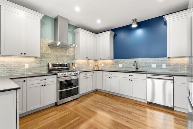 132 Sewall St Unit C, Brookline, MA 02446 - kitchen featuring stainless steel appliances, wall chimney exhaust hood, a sink, decorative backsplash, and dark countertops