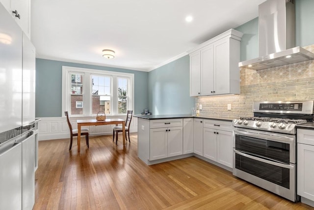 132 Sewall St Unit C, Brookline, MA 02446 - kitchen featuring appliances with stainless steel finishes, wall chimney exhaust hood, a peninsula, decorative backsplash, and light wood finished floors