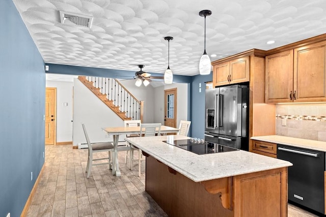 kitchen with tasteful backsplash, black appliances, decorative light fixtures, light hardwood / wood-style floors, and a center island