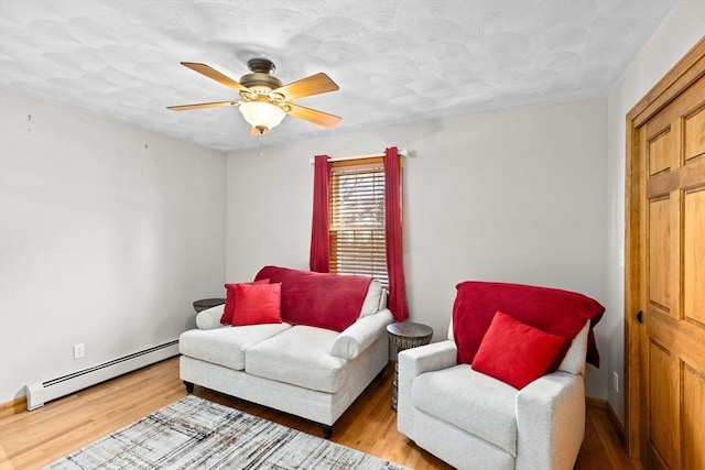 living area featuring hardwood / wood-style floors, ceiling fan, and a baseboard radiator