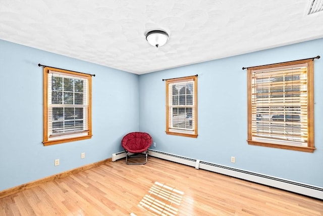 unfurnished room with light hardwood / wood-style floors, a textured ceiling, and a baseboard heating unit