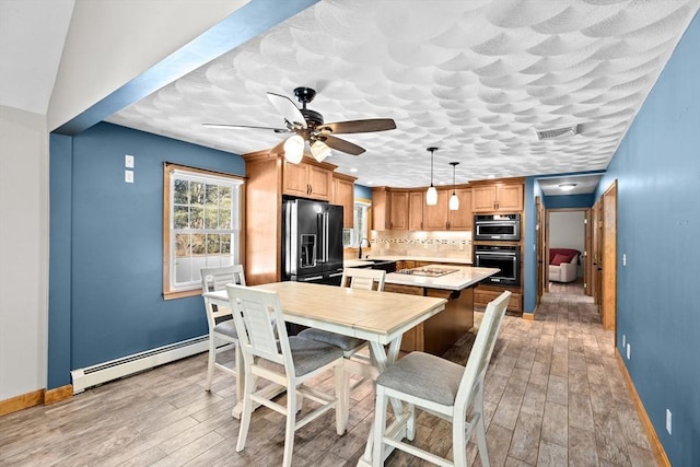 dining room with light wood-type flooring, sink, a baseboard heating unit, and ceiling fan