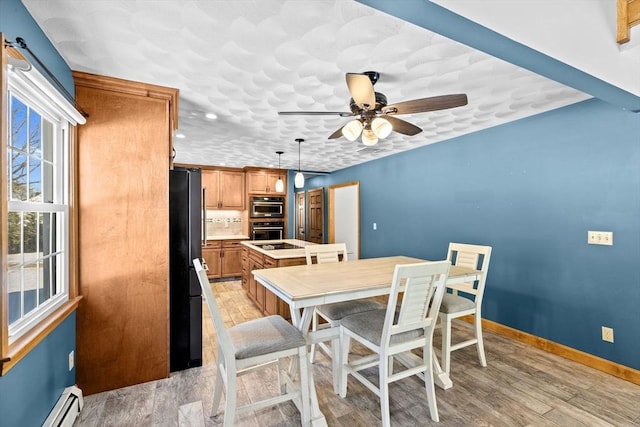 dining room featuring light hardwood / wood-style floors, ceiling fan, and a baseboard radiator