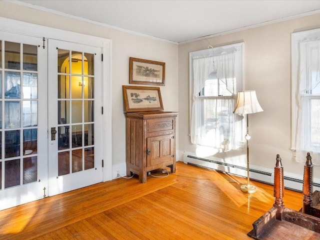 interior space with french doors, ornamental molding, a baseboard heating unit, and hardwood / wood-style flooring