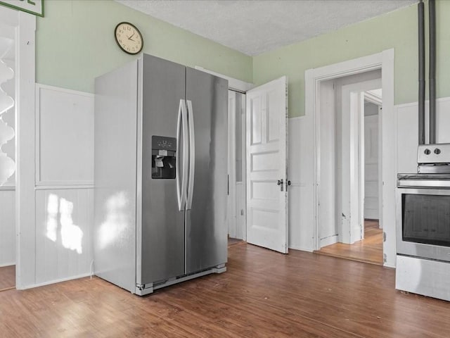 kitchen with stainless steel fridge, stove, hardwood / wood-style floors, and a textured ceiling