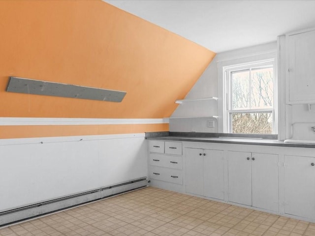 kitchen featuring vaulted ceiling, white cabinetry, and a baseboard radiator