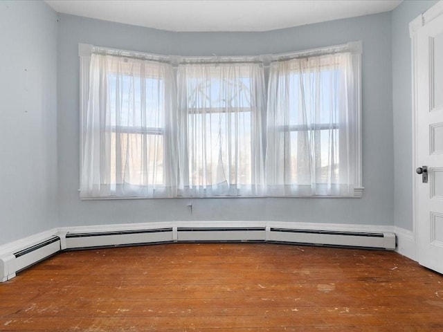 unfurnished room featuring baseboard heating and hardwood / wood-style floors