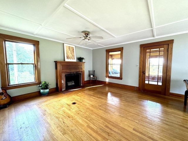 unfurnished living room with a brick fireplace, ceiling fan, plenty of natural light, and light hardwood / wood-style flooring