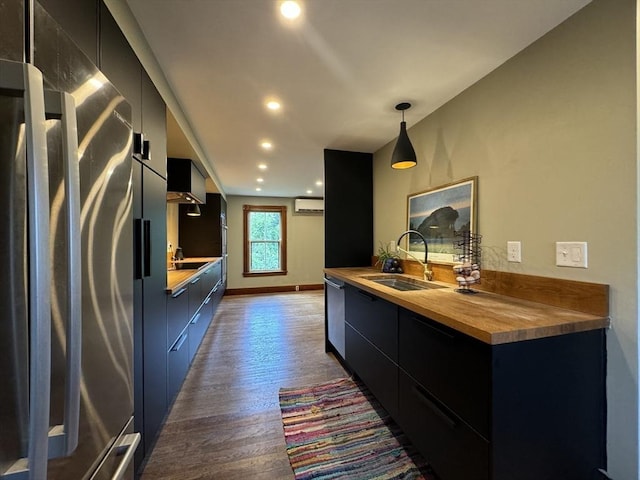 kitchen featuring sink, butcher block countertops, a wall unit AC, refrigerator, and decorative light fixtures