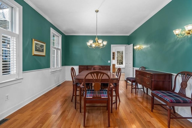 dining area featuring ornamental molding, wood finished floors, and a notable chandelier