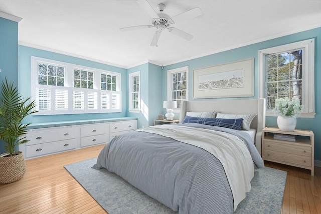 bedroom featuring hardwood / wood-style flooring, ornamental molding, and a ceiling fan