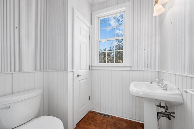 bathroom featuring a wainscoted wall, visible vents, and toilet