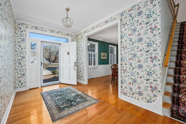 foyer entrance featuring ornamental molding, light wood-style flooring, stairway, and wallpapered walls