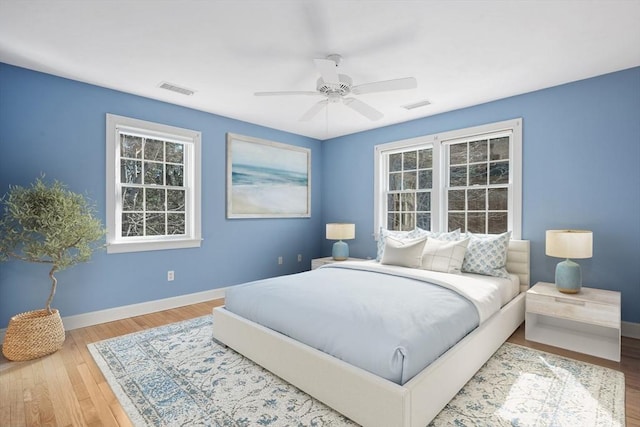 bedroom with baseboards, visible vents, ceiling fan, and wood finished floors