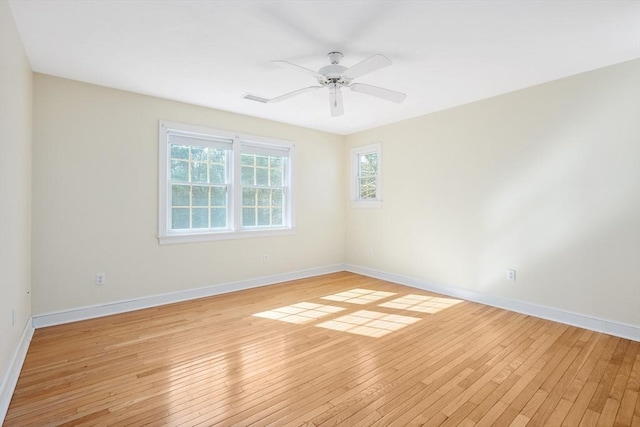 spare room featuring light wood-style floors, visible vents, baseboards, and a ceiling fan