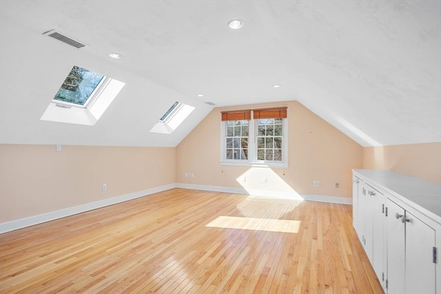 additional living space featuring baseboards, visible vents, lofted ceiling, light wood-type flooring, and recessed lighting