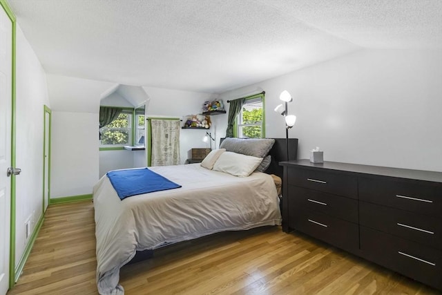 69 Powder Mill Rd, Maynard, MA 01754 - bedroom featuring vaulted ceiling, light wood-style flooring, a textured ceiling, and multiple windows