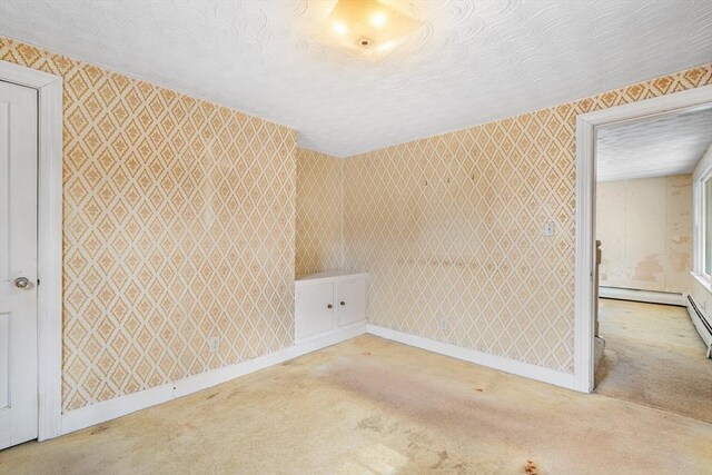 spare room with a textured ceiling, baseboards, carpet flooring, and wallpapered walls