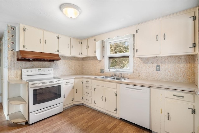 kitchen with under cabinet range hood, white appliances, a sink, light countertops, and light wood-type flooring