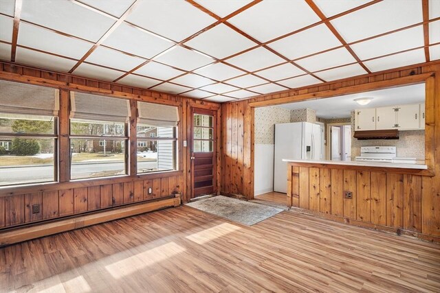 interior space featuring wood walls, light wood-style flooring, and baseboard heating