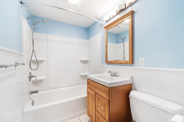 bathroom featuring toilet, vanity, shower / washtub combination, wainscoting, and tile patterned floors