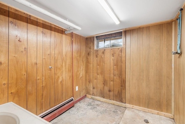 interior space featuring unfinished concrete flooring, a baseboard radiator, and wooden walls