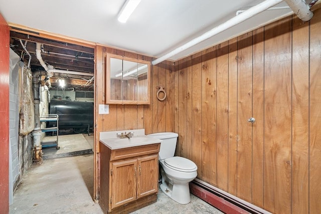 bathroom with toilet, wood walls, vanity, concrete floors, and heating fuel