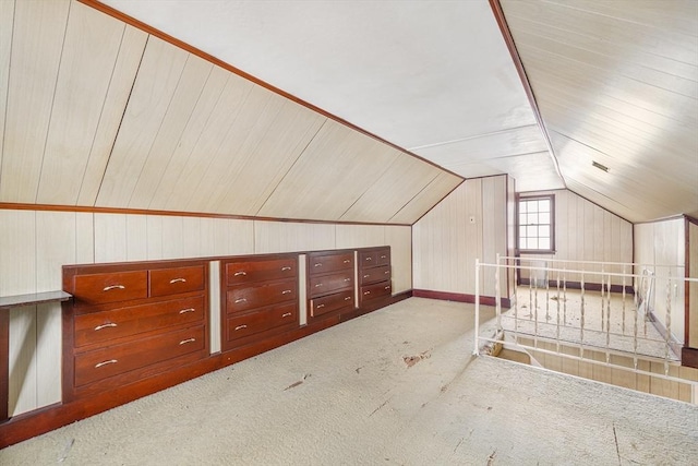 additional living space featuring lofted ceiling, carpet flooring, and wooden walls